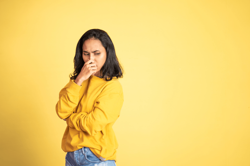 Woman pinching nose, disgusted by a bad smell
